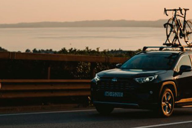 Ciemna Toyota jadąca o zachodzie słońca z rowerami na dachu