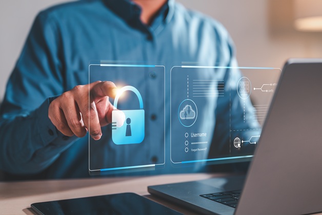 Mężczyzna korzystający z laptopa z widoczną grafiką kłódki symbolizującą bezpieczeństwo danych.