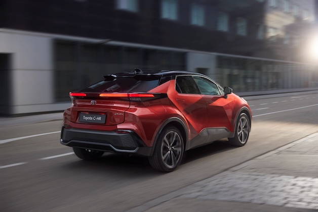 Czerwona Toyota C-HR podczas jazdy miejskiej, zdjęcie wykonane jest od tyłu