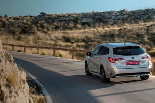 Srebrna Toyota jadąca na zakręcie drogi wśród zieleni
