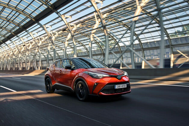 Pomarańczowa Toyota C-HR jadąca trasą w oszklonym tunelu, widok z przodu