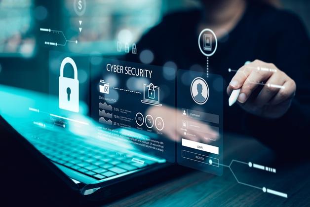 Zdjęcie wizualizuje cyberbezpieczeństwo, z ikonami kłódek i polami do logowania. Na zdjęciu widoczne są dłonie, które rysikiem piszą na wirtualnym panelu na laptopie.