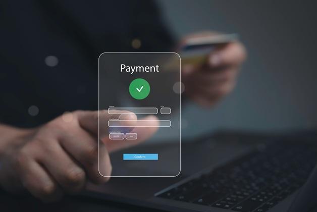 Koncepcja bezpiecznej płatności cyfrowej. Zbliżenie na dłoń wpisującą dane karty kredytowej (numer, data ważności, CVC) do internetowego formularza "Payment" z symbolem sukcesu.