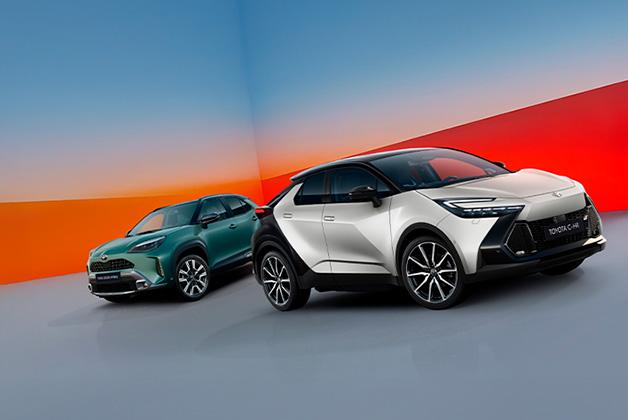 Dwie nowe Toyoty C-HR, jedna w jasnym kolorze, druga w zielonym, zaprezentowane na tle z gradientem od niebieskiego do czerwonego.