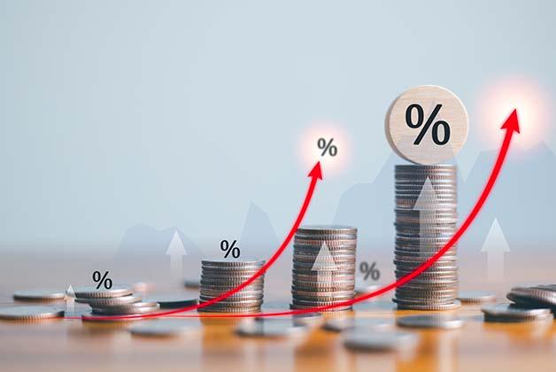 Rosnące stosy monet ze strzałką w górę i symbolami procentów, ilustrujące wzrost finansowy, zyski z inwestycji lub rosnące stopy procentowe.