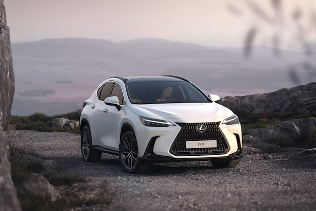 Biały SUV Lexus NX zaparkowany na kamienistej drodze na tle zamglonych wzgórz.