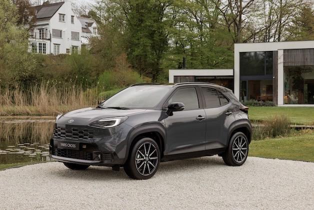 Nowoczesny miejski crossover Toyota Yaris Cross w kolorze ciemnoszarym na tle nowoczesnego domu i stawu